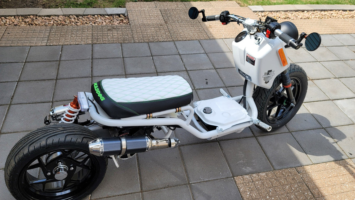 White Maddog scooter with a white diamond-stitched seat cover featuring green stitching and green MADDOG embroidery, handmade by Cheeky Seats
