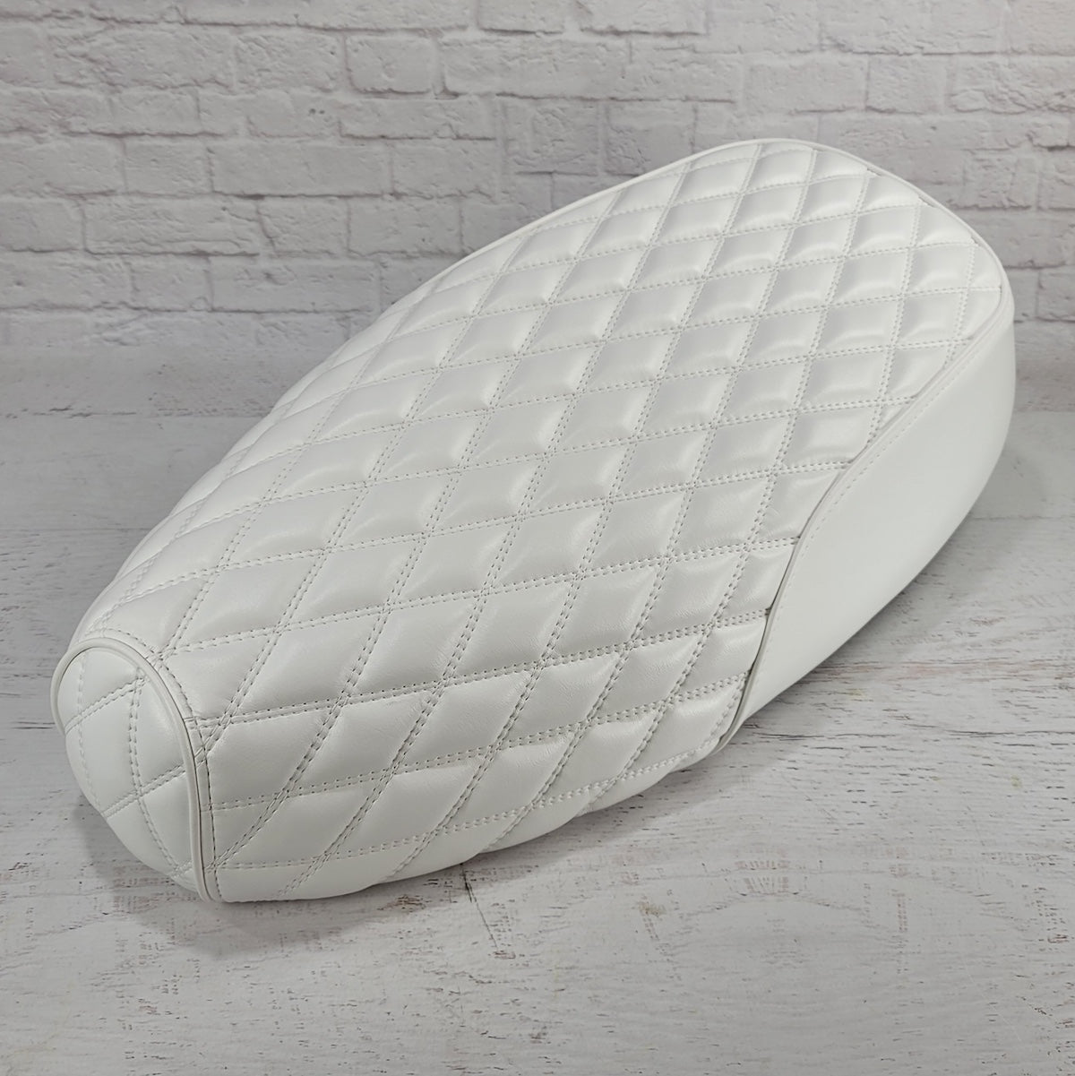 High front angle of a white Genuine Buddy Kick 125 seat cover with white double-diamond stitching, handmade by Cheeky Seats
