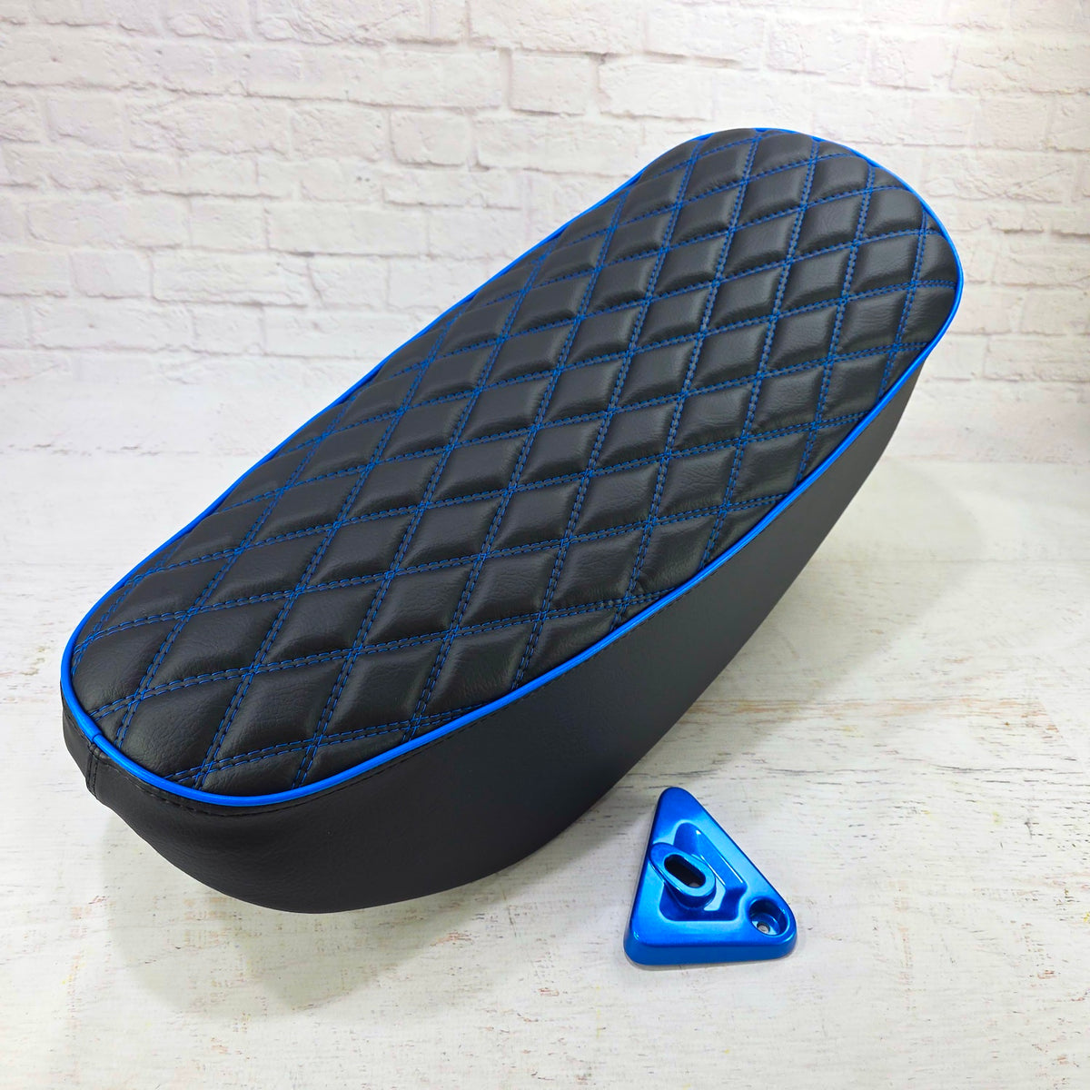Black double-diamond Honda DAX 125 seat cover with electric blue stitching, piping and matching lock bracket, handmade by Cheeky Seats