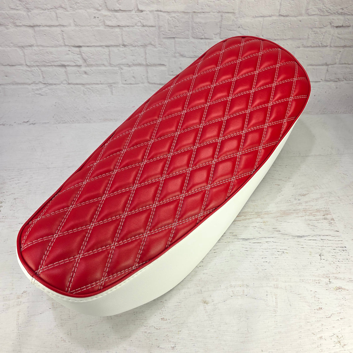 Red diamond seat cover for the Honda DAX 125 with white double stitching, red piping and white sides, handmade by Cheeky Seats
