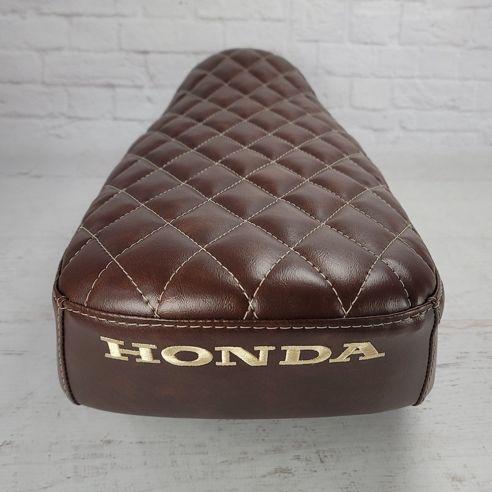 Rear view of a whiskey brown diamond Honda DAX 125 seat cover with gold Honda embroidery, handmade by Cheeky Seats