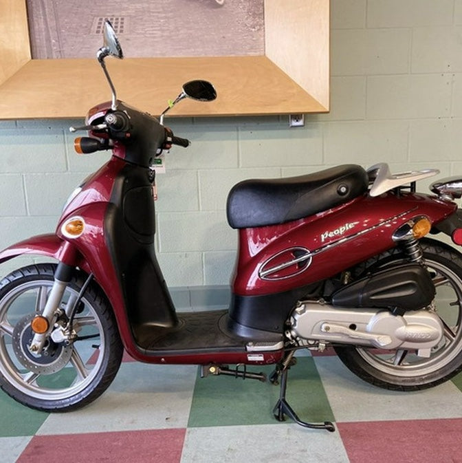 Full side view of a burgundy Kymco People 50 with a fitted black seat cover installed, People branding visible on the side panel