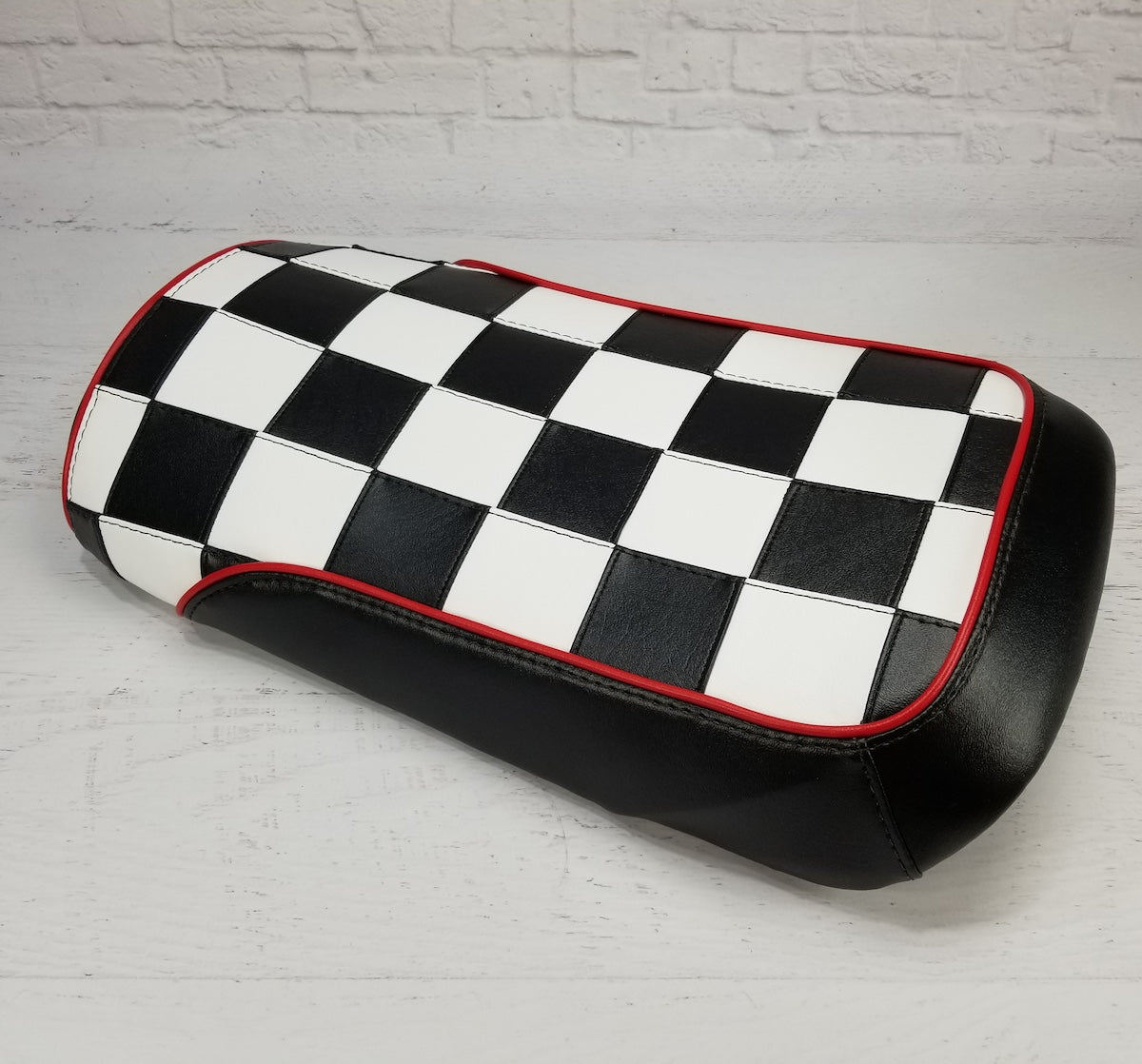 Front three-quarter view of the black and white checkerboard seat cover with red piping and black side panels, handmade by Cheeky Seats