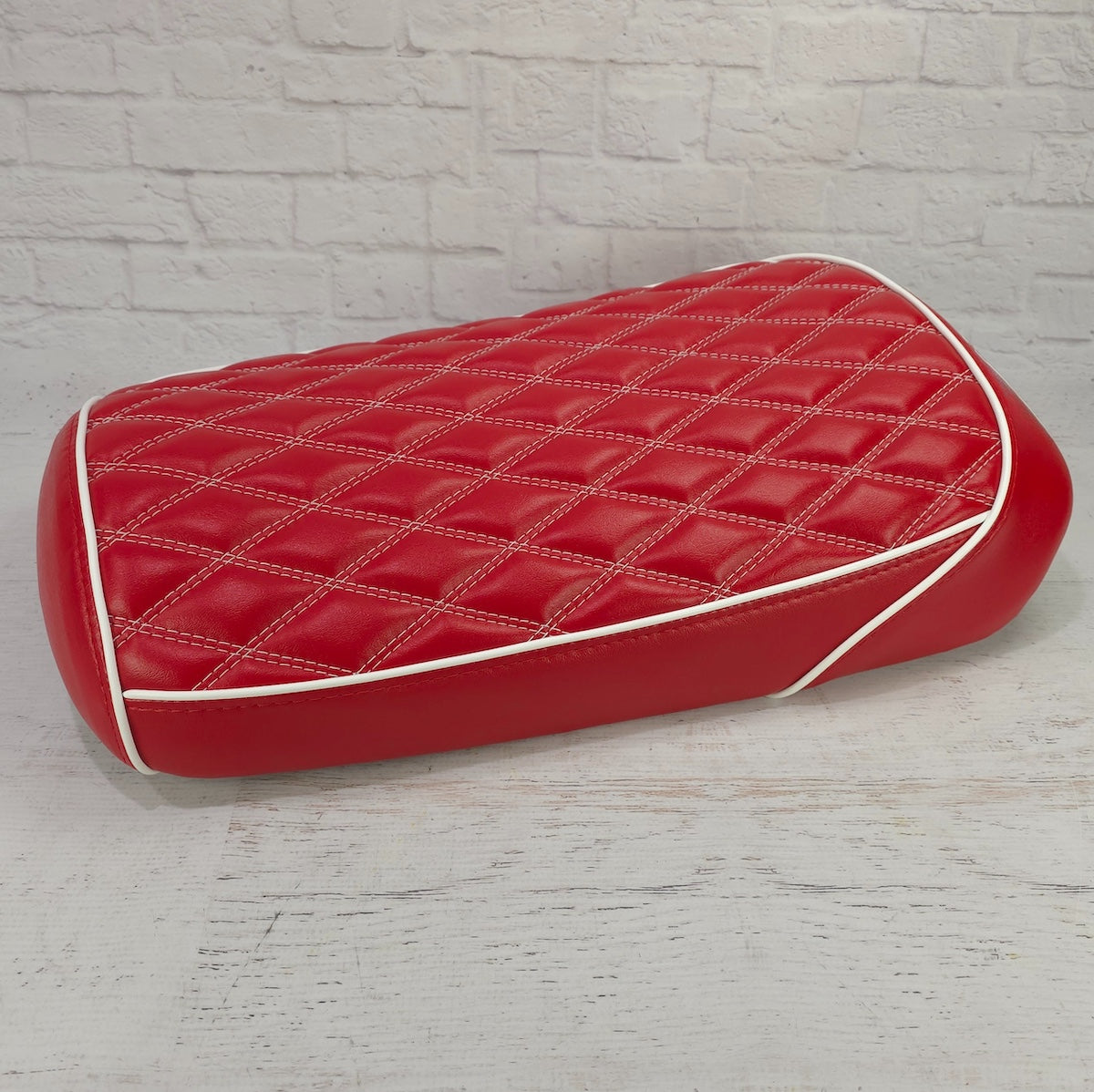 Rear three-quarter view of the red diamond seat cover with white piping trim