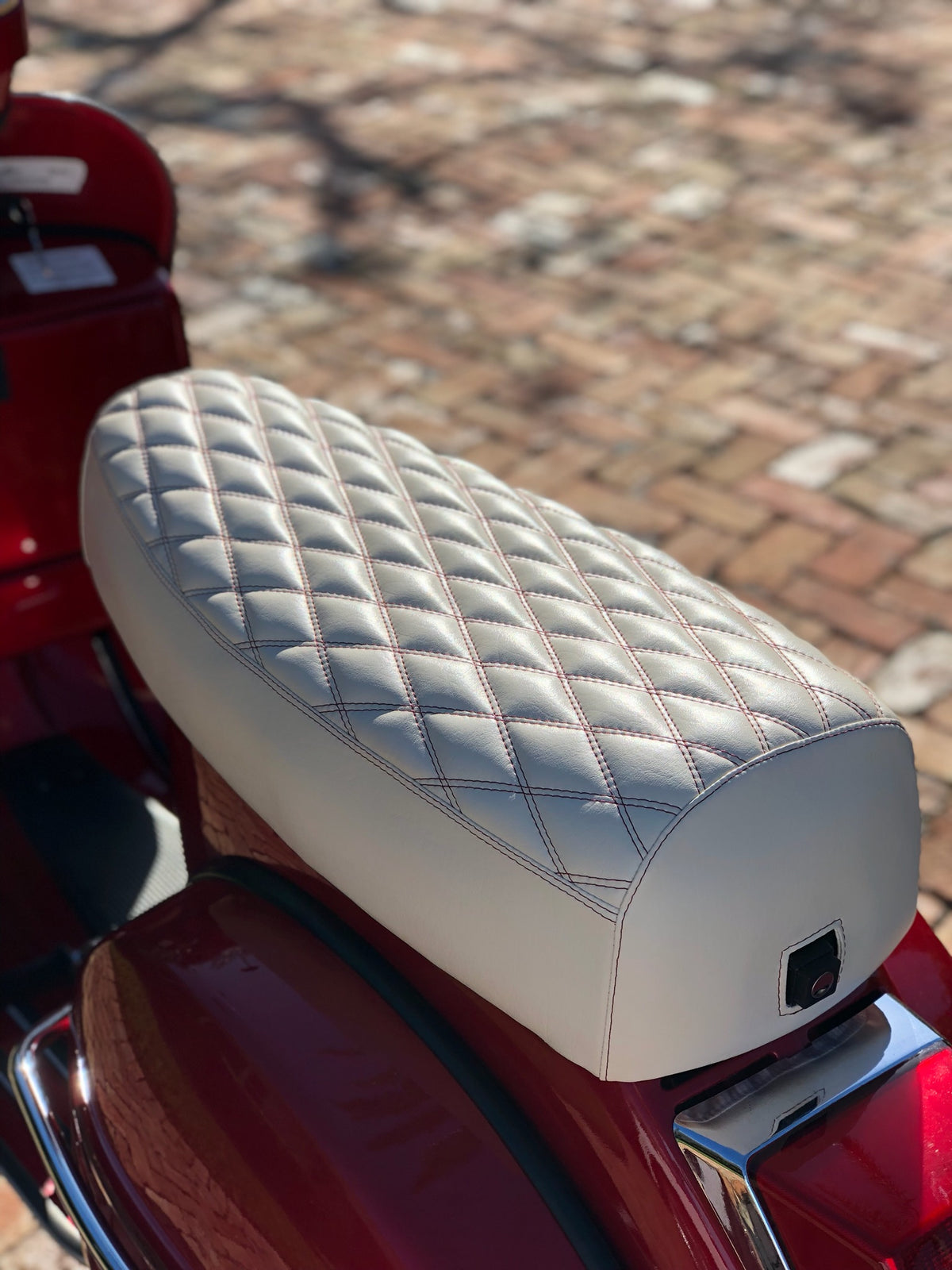 Close-up of a cottage-white diamond-stitched Cheeky Seats cover fitted to a red Genuine Stella