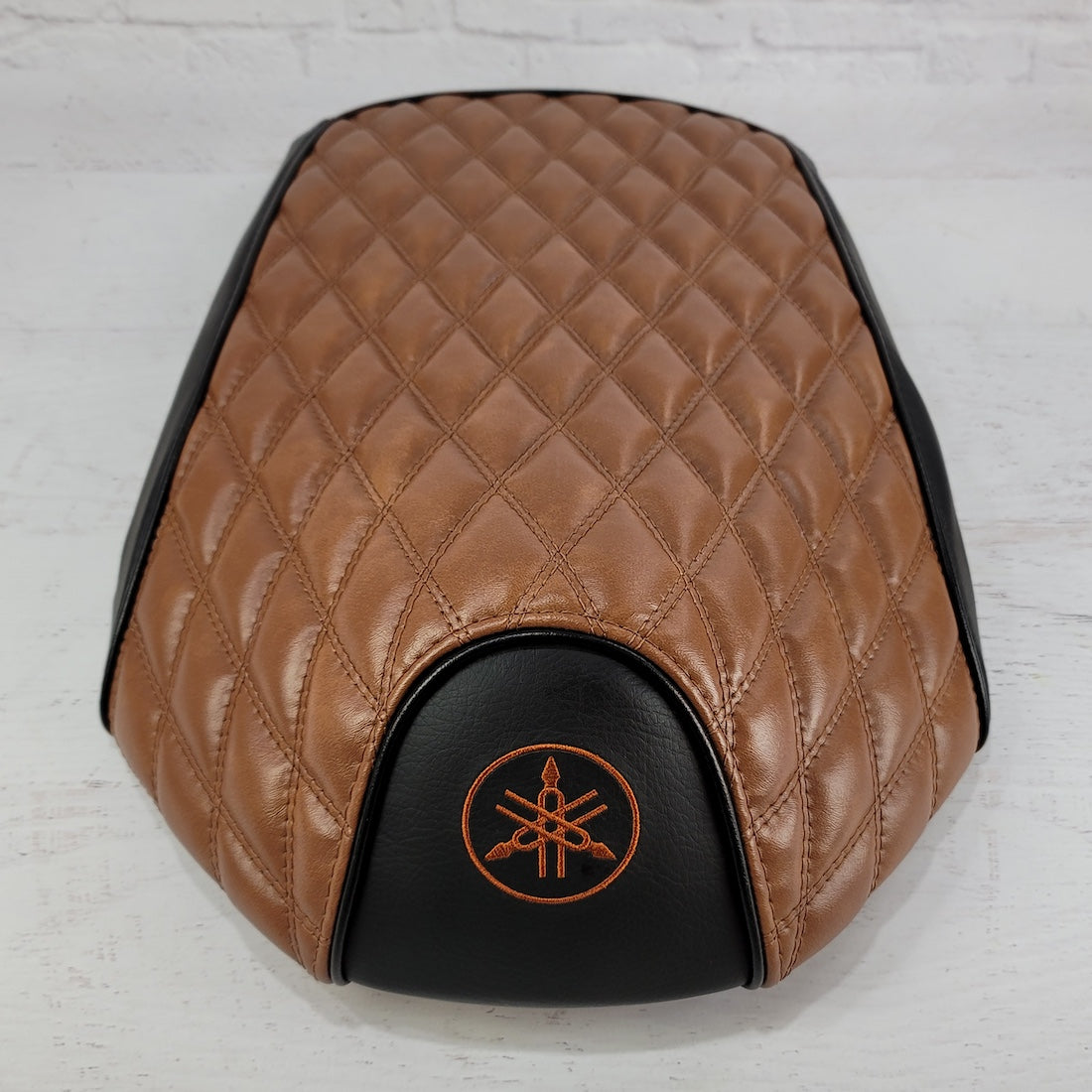 Front view of the Black and Tan Yamaha C3 seat cover highlighting the diamond quilting and orange Yamaha embroidery, handmade by Cheeky Seats.