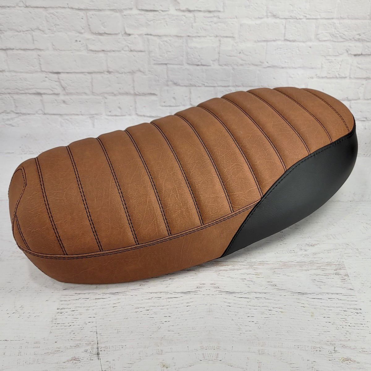 Rear three-quarter view of an anti-slip distressed Slickrock brown Yamaha Zuma II BWS 49/50 Prebug seat cover with tuck-and-roll stitching and black side panels, handmade by Cheeky Seats
