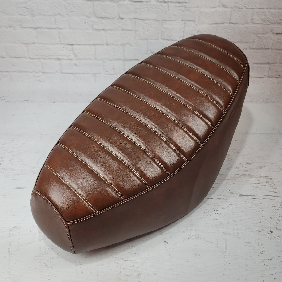 Whiskey-brown padded tuck-and-roll Cheeky Seats cover for a Genuine Buddy, front studio angle