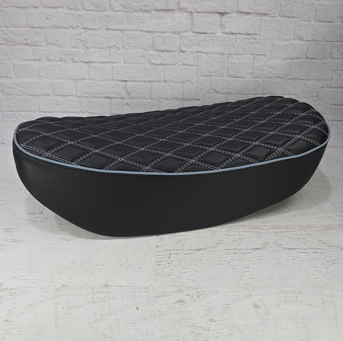 Low side view of a black double-diamond Honda DAX 125 cover with white stitching and pale blue piping, handmade by Cheeky Seats