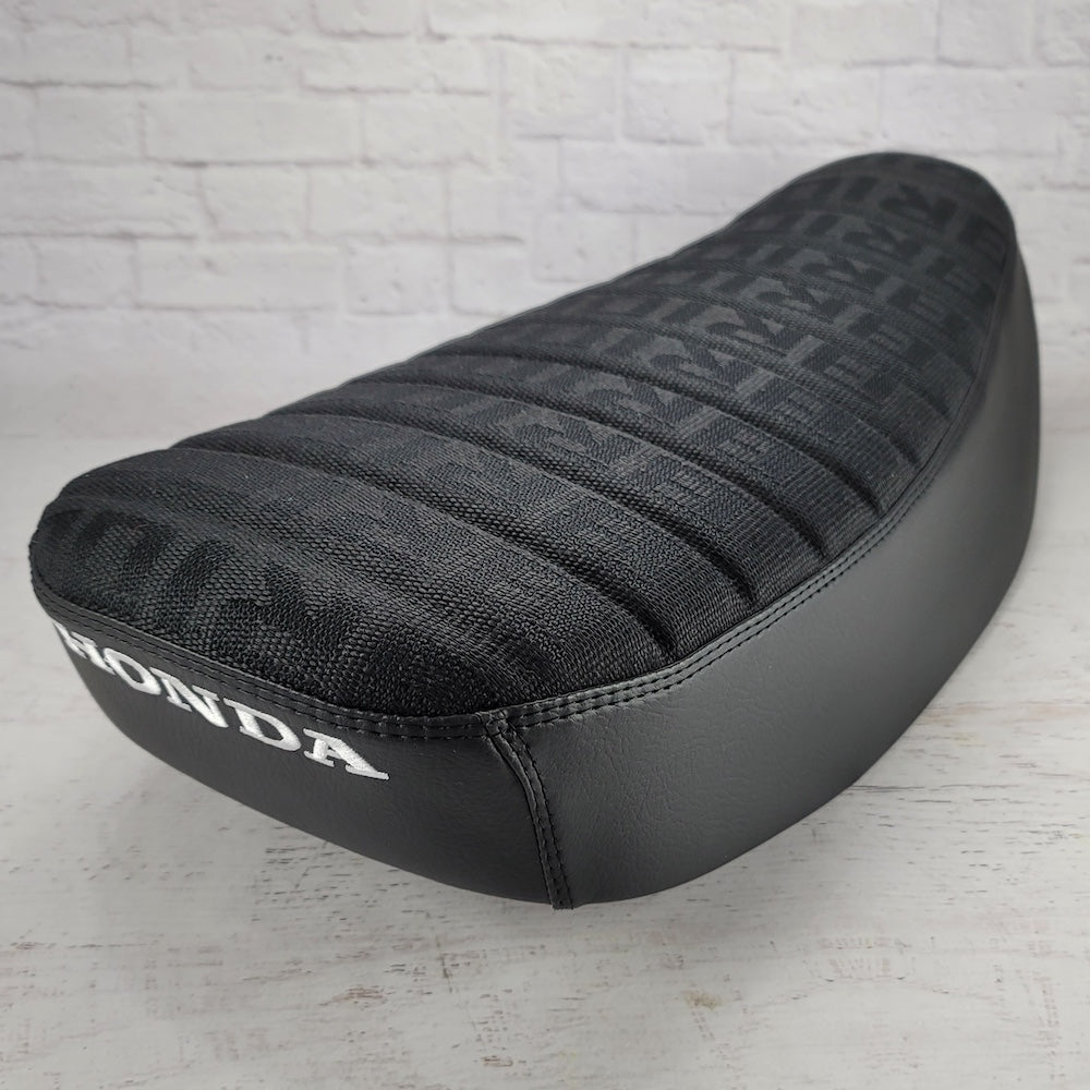 Rear angled view of a black BRIDE Honda DAX 125 cover with white embroidered Honda logo, handmade by Cheeky Seats
