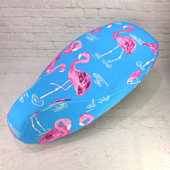 Blue Vepa seat cover with pink flamingo pattern on a white brick wall background