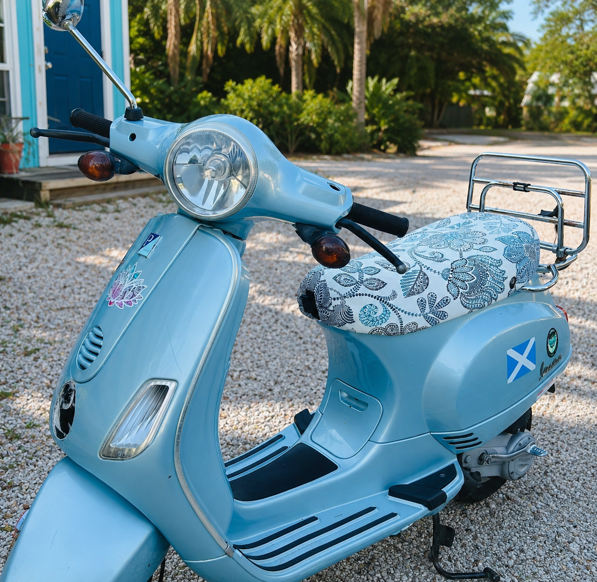 Blue and Cream Flowers seat cover fitted to a light blue Vespa LX, adding a refined botanical finish, handmade by Cheeky Seats.