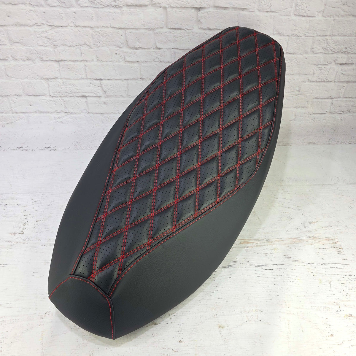 Black Yamaha Zuma 50 Double Diamond seat cover with a perforated center and red contrast stitching, handmade by Cheeky Seats.