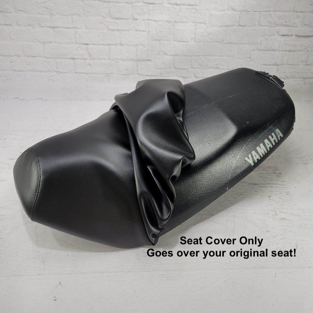 Black Yamaha Zuma 50 seat cover shown partially removed to demonstrate that the cover fits over the original scooter seat, handmade by Cheeky Seats.