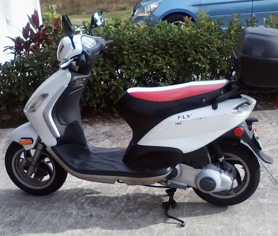 White Piaggio Fly 150 with a green, white and red Italian flag seat cover and rear top case, handmade by Cheeky Seats