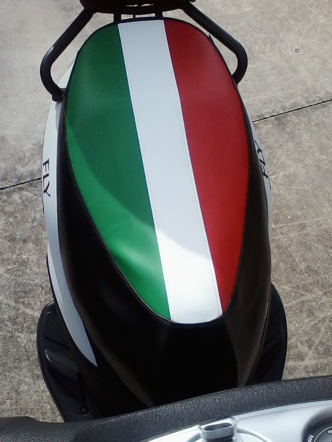 Overhead view of an Italian tricolor seat cover installed on a white Piaggio Fly scooter, handmade by Cheeky Seats