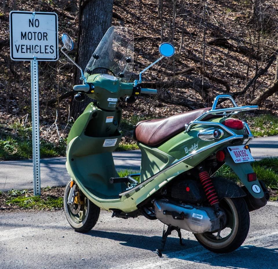 Green Genuine Buddy with a whiskey-brown Cheeky Seats cover, rear three-quarter roadside view