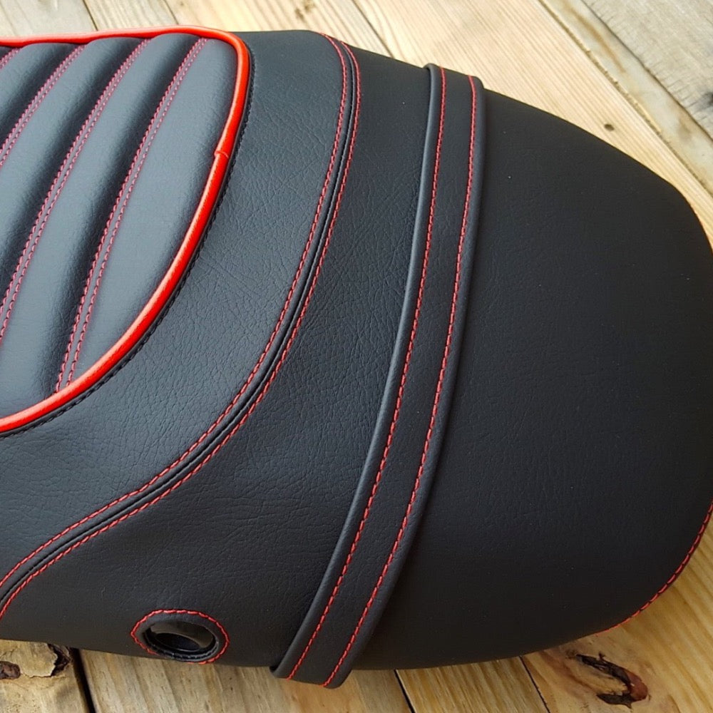 Close-up of black Vespa S seat cover showing red stitching, piping, strap and lock opening by Cheeky Seats