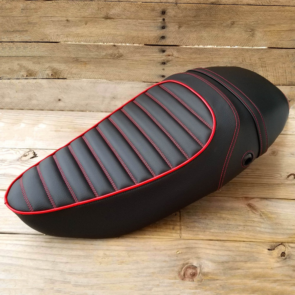 Angled black Vespa S tuck-and-roll seat cover with red piping, stitching and strap by Cheeky Seats